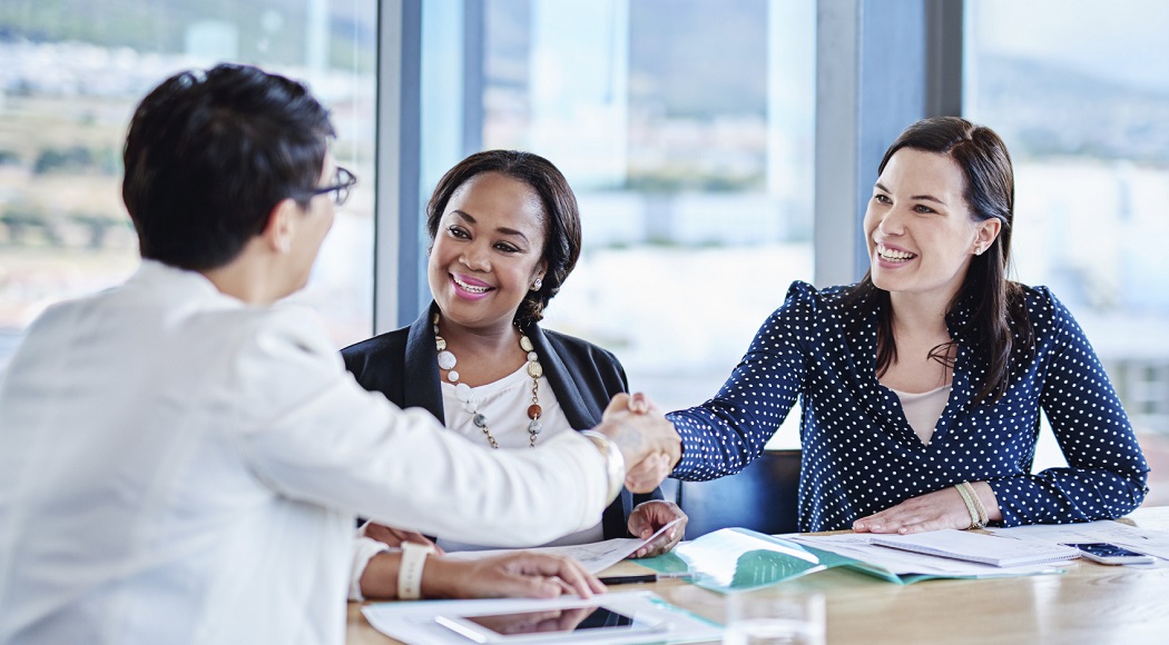 One staff member asks questions about a plan around a table with other staff members