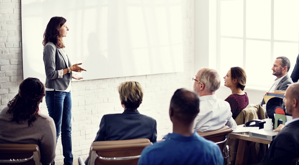 One teacher with a whiteboard and businessmen and women listening